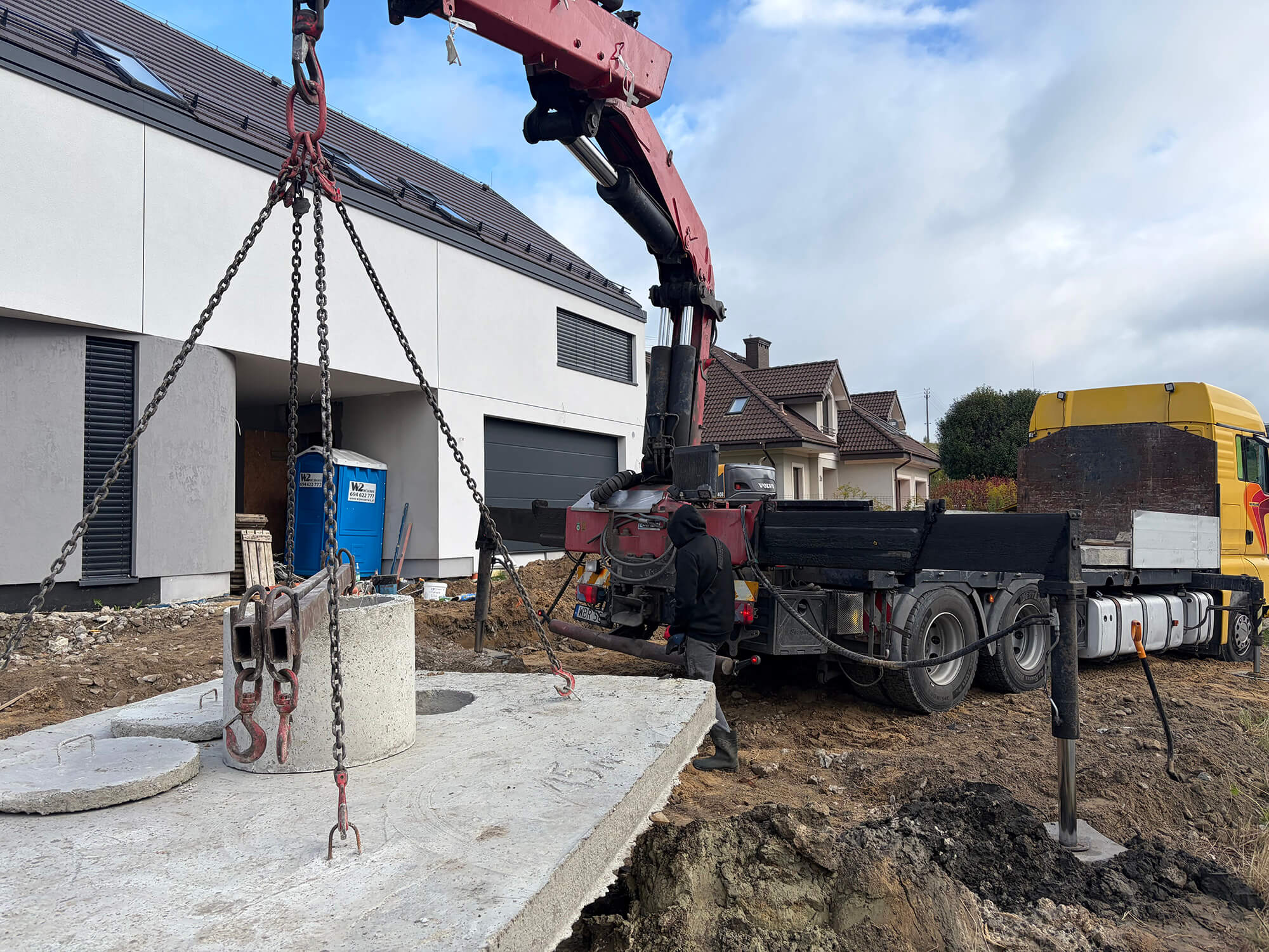 Szambo betonowe 10 m³ opuszczane za pomocą HDS do wykopu w Białobrzegach